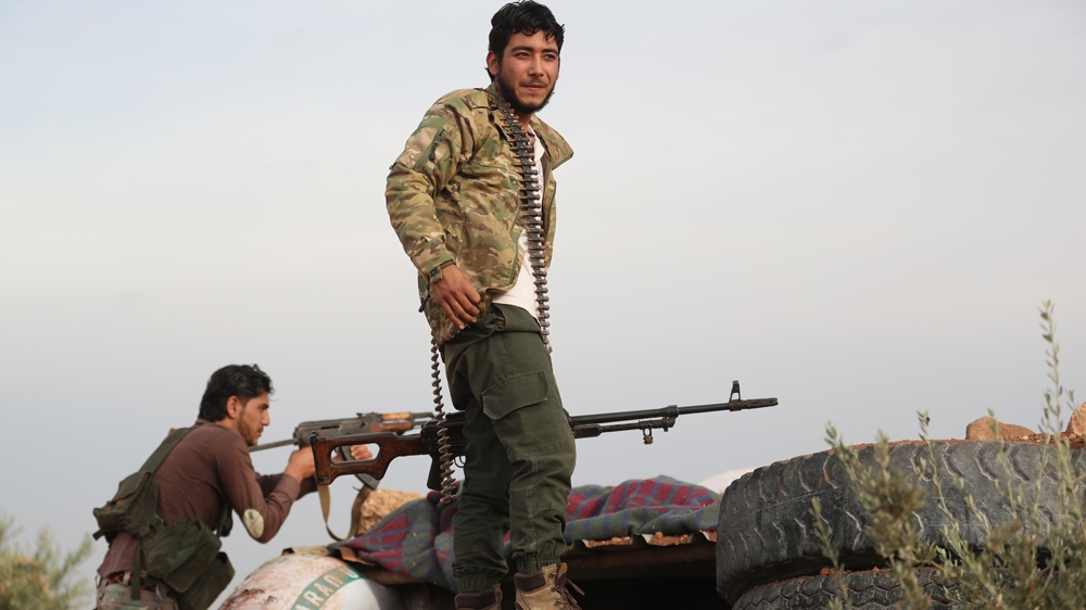 Fighters from the NLF gather on the front line with Syrian government forces in October [Omar Haj Kadour/AFP]