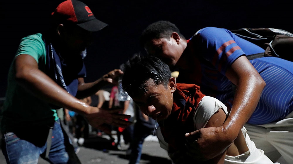 A man washes his face from gas during a clash with the Mexican Police after they pull down the border gate with the intention to carry on their journey, in Tecun Uman, Guatemala [Carlos Garcia Rawlins/Reuters]