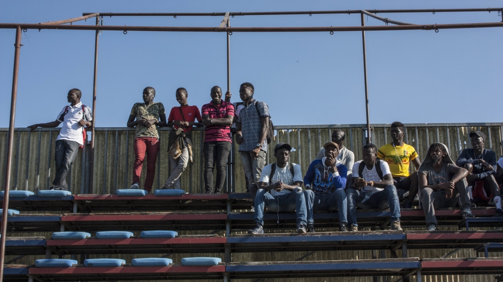 Many of St. Ambroeus FC’s players can’t play today – the Italian football federation hasn’t cleared their signing yet. They gather with friends to watch teammates from a distance. [Alessio Perrone/Al Jazeera] [Al Jazeera]