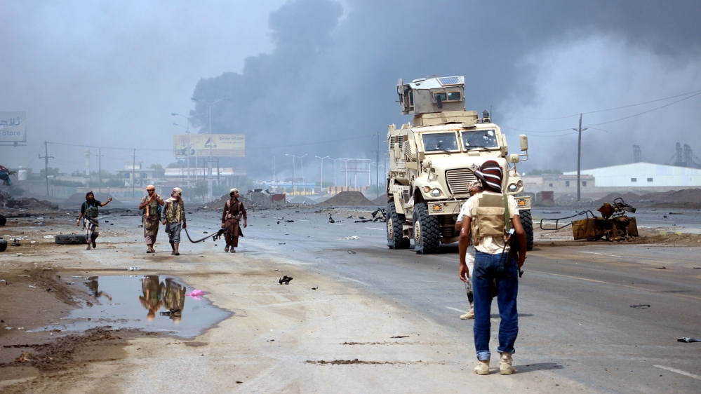 Yemeni government forces patrol as smoke billows from an alleged Houthi position during battles between Yemeni government forces and Houthi rebels in the port city of Hodeidah