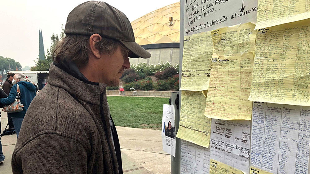 Wildfire evacuee Greg Gibson looks for information about his missing neighbours [Gillian Flaccus/AP]
