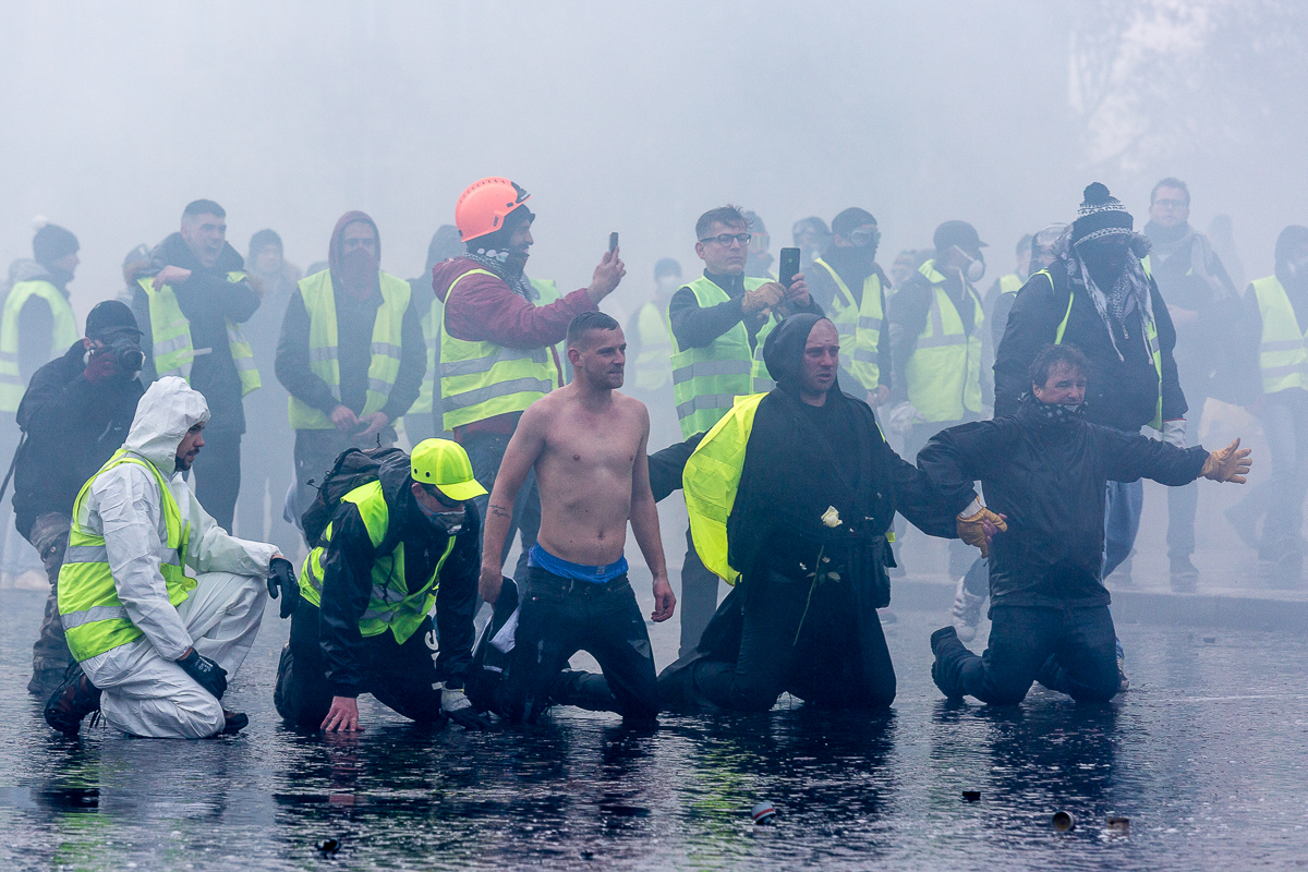 A group of protesters knee in from of police forces moments before of being hit by a water cannon during a demonstration near the Champs ElysE`es called for by the i`Gilets Jaunesi^ movement on Decemb