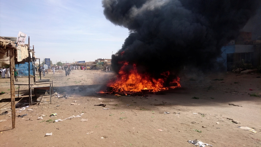 A bonfire is lit along the street during protests against price increases in Atbara