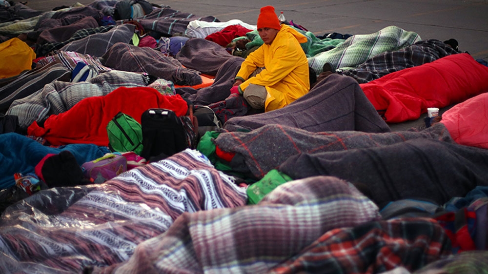 Migrants and refugees rest as they wait at the El Chaparral port of entry border crossing between Mexico and the United States [Hannah McKay/Reuters] 