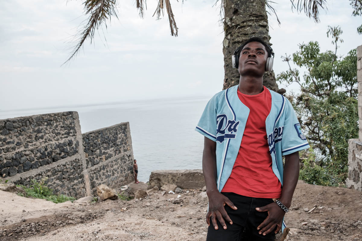Enoke-B (24) lives right on the shores of Lake Kivu, surrounded by large misty mountains on the border with Rwanda. Big NGOs and UN agencies have their offices right in front of his “doorstep”.