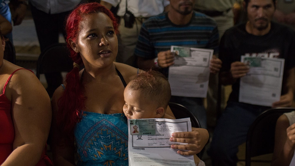 A group of Central Americans display their humanitarian visas shortly after receiving them from the Mexican government [Jeff Abbott/Al Jazeera] 
