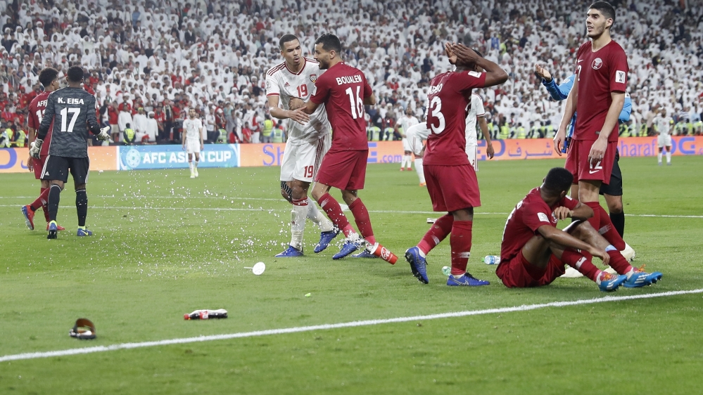 Qatar's defender Salem Al Hajri sits on the pitch after shoes and bottles where thrown by UAE fans during the semi-final [Hassan Ammar/Reuters]