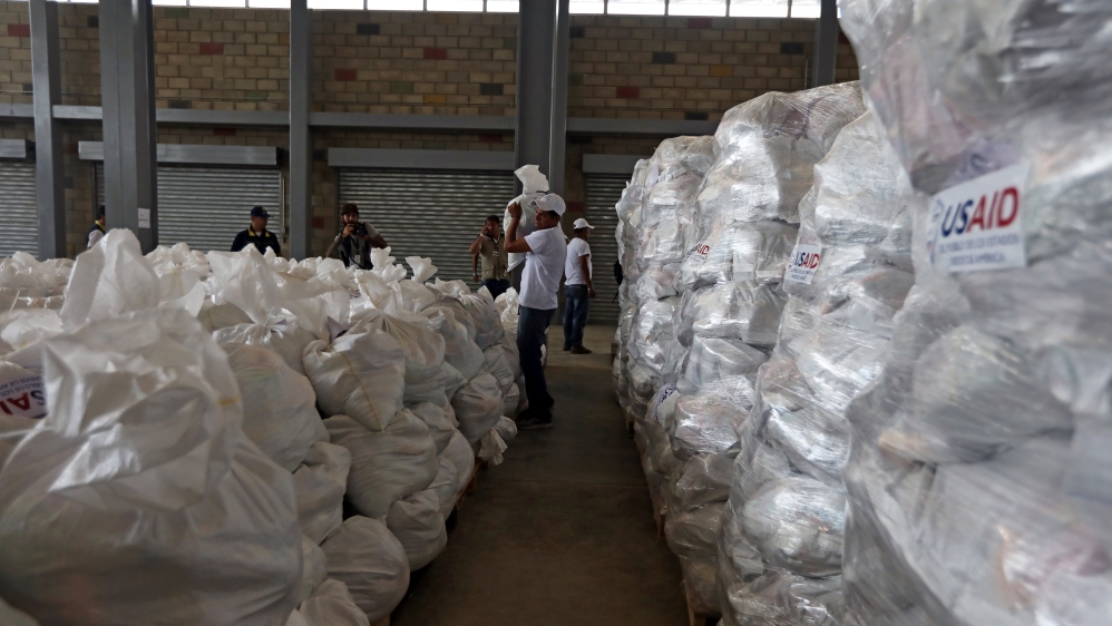 Volunteers were busily filling white sacks with the items from boxes marked with the words 'USAID' [Luisa Gonzalez/Reuters]