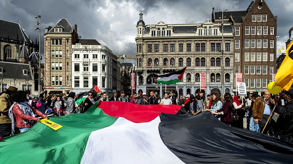 People hold a big Palestinian flag and signs during a demonstration against Israel''s military operations in Gaza and in support of the Palestinian people, in Amsterdam, The Netherlands, on 23 August 2