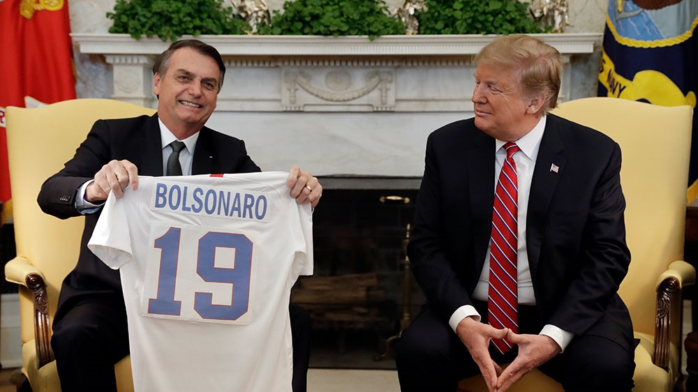 Trump and Bolsonaro exchanged football shirts in the Oval Office. [Evan Vucci/AP Photo]
