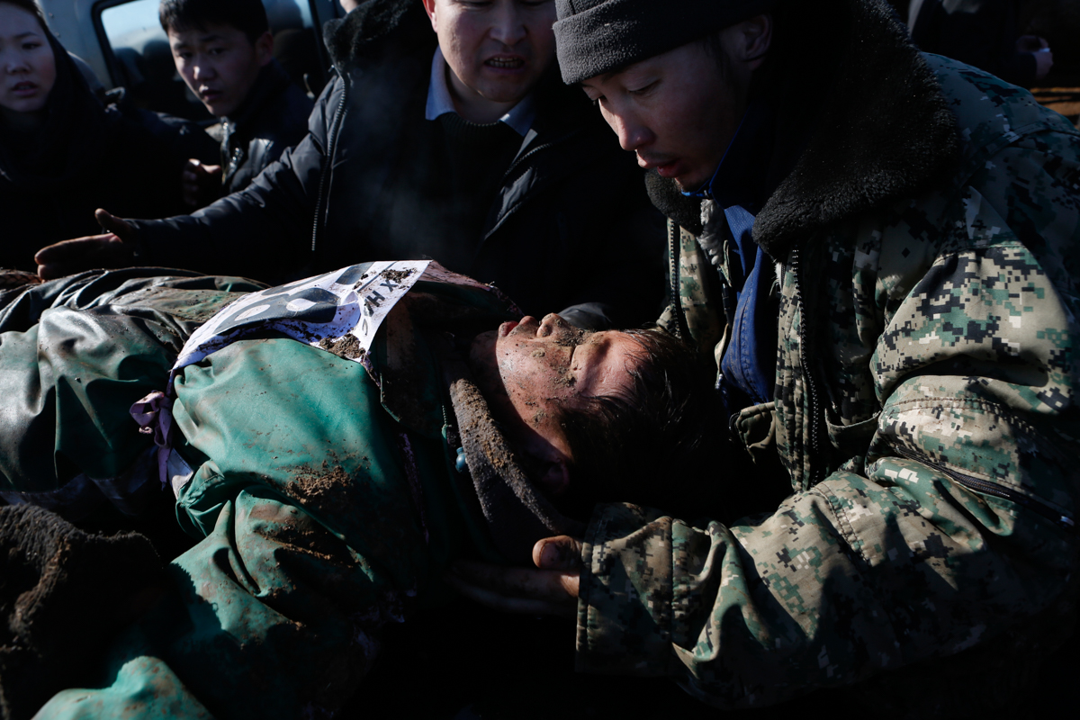 Trainers deliver first aid to an injured rider. The child fell from his horse when crowds swarmed him, trying to touch his horse for good luck. [Davaanyam Delgerjargal/Al Jazeera]