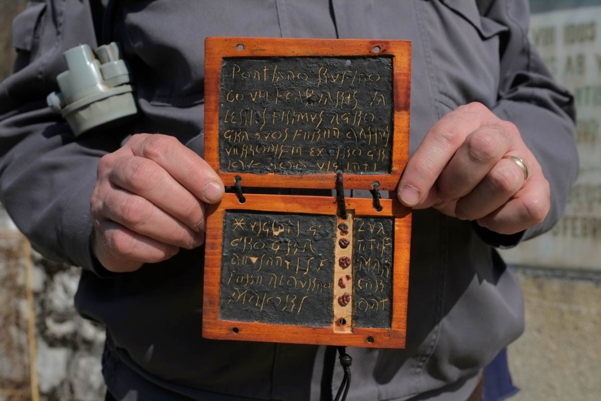 A local guide for the state museum in Ro?ia holds up a replica of a Roman wax tablet found in the Roman galleries. The particularity of the tablets, as opposed to others found across the range of the