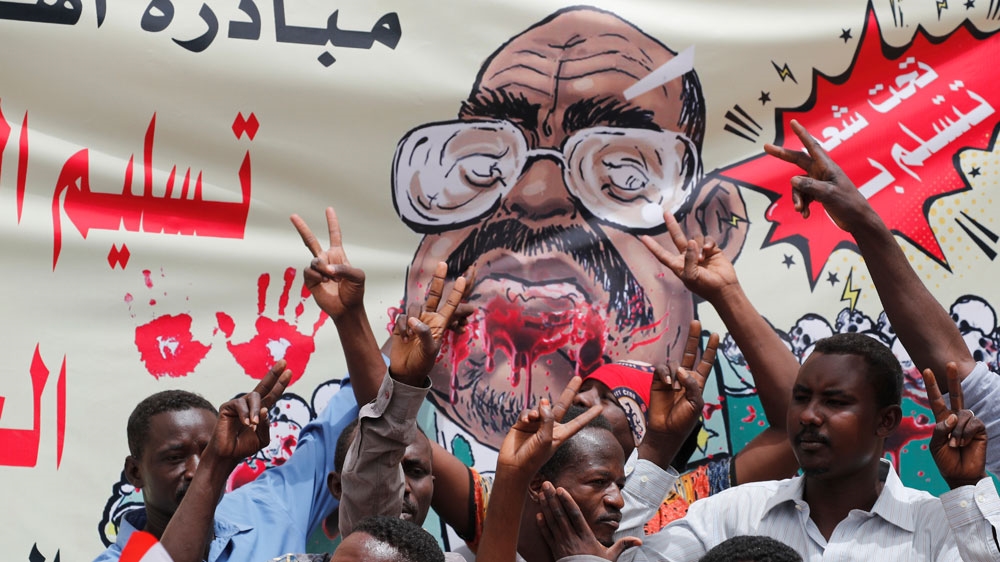 Protesters shout slogans by a banner depicting former Sudanese President Omar al-Bashir, in front of the Defence Ministry in Khartoum [Umit Bektas/Reuters]