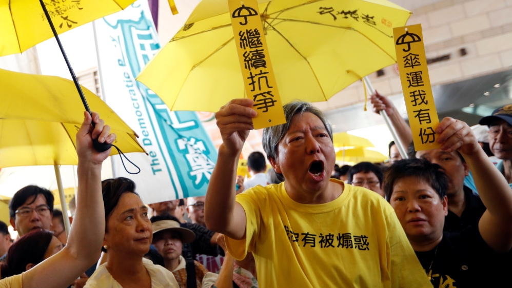 Pro-democracy supporters and activist Lee Cheuk-yan (front) hold yellow umbrellas and placards to support leaders of the Occupy Central activists [Tyrone Siu/Reuters]