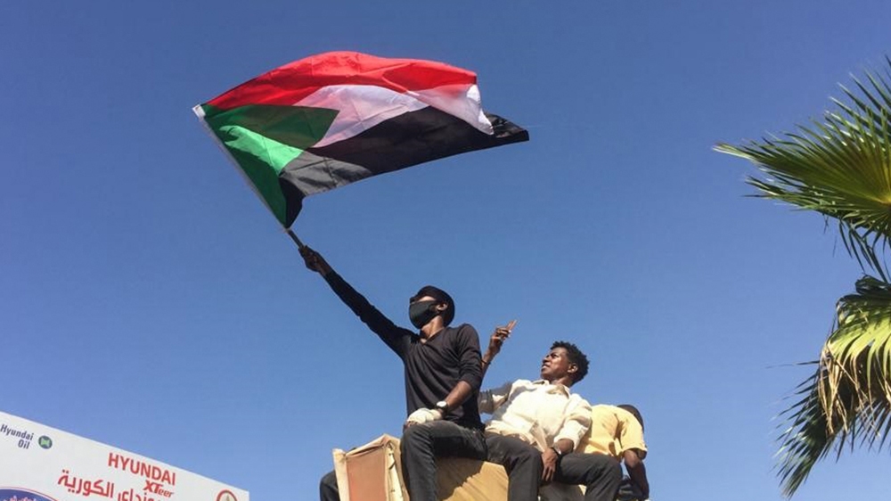 A Sudanese protester waves the national flag as they rally for a second day outside the military headquarters in the capital Khartoum on April 7, 2019. - Sudanese police fired tear gas at thousands of