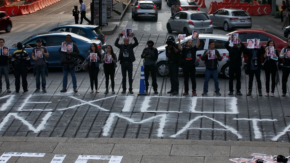 Journalists hold up photos of slain journalists during a protest to call attention to the killings of journalists in Mexico