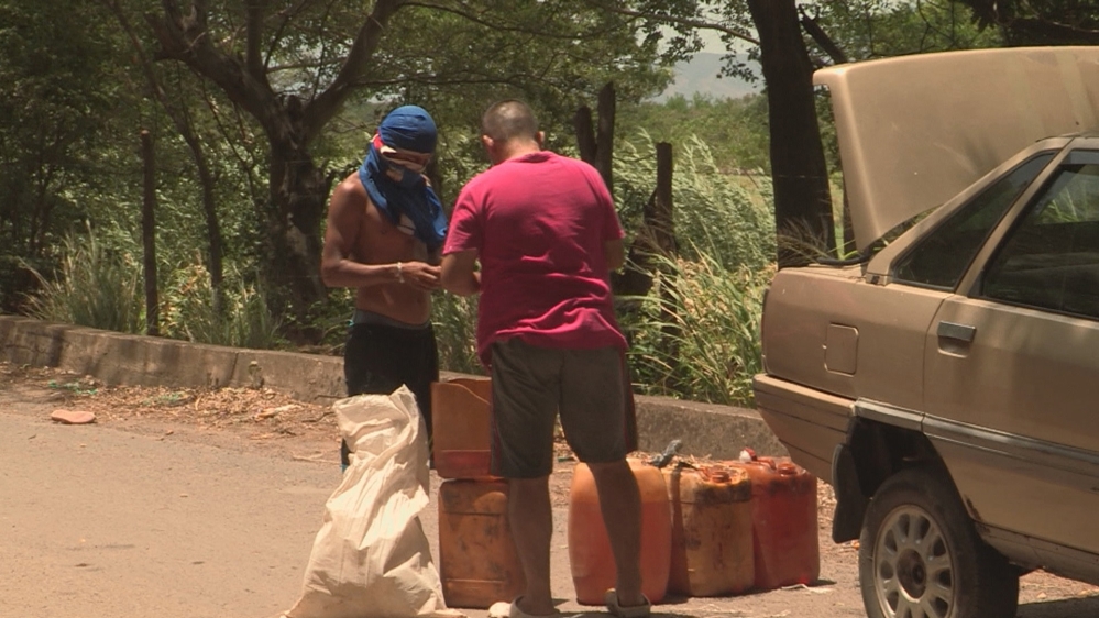 A petrol smuggler exchanges fuel with a trafficker along the Venezuela-Colombia border