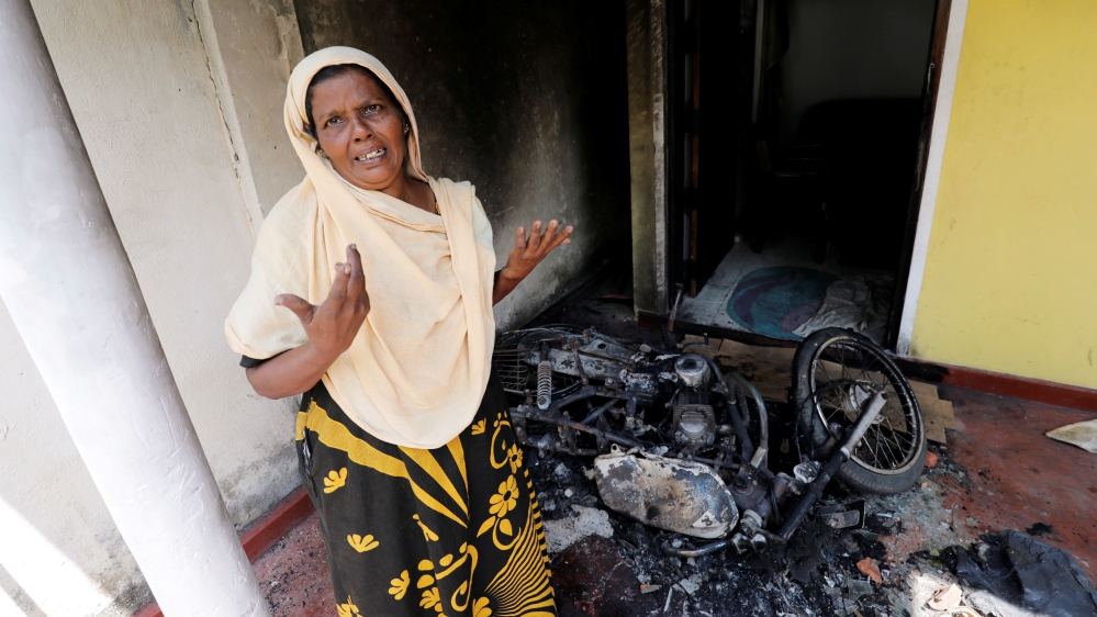 A Muslim woman reacts next to a burnt motorbike and her house after a mob attack in Kottampitiya