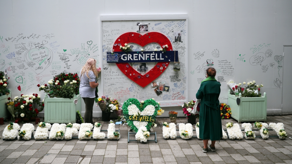 Women looks at a hoarding covered in messages of condolence at the base of Grenfell tower two years after the fire in London