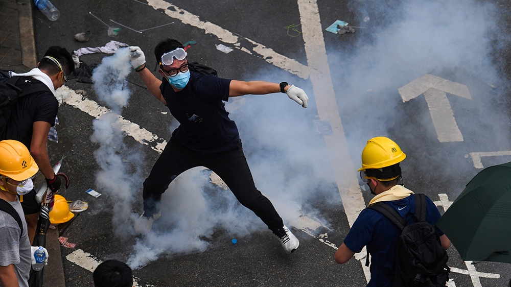 A protester throws back a tear gas during clashes with police outside the government headquarters in Hong Kong on June 12, 2019. - Violent clashes broke out in Hong Kong on June 12 as police tried to