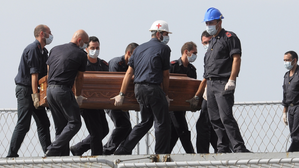 The casket of one of the migrants who died when their boat capsized off in the Canal of Sicily is carried aboard a Italian Navy ship at the Lampedusa island harbor, Saturday, Oct. 12, 2013.