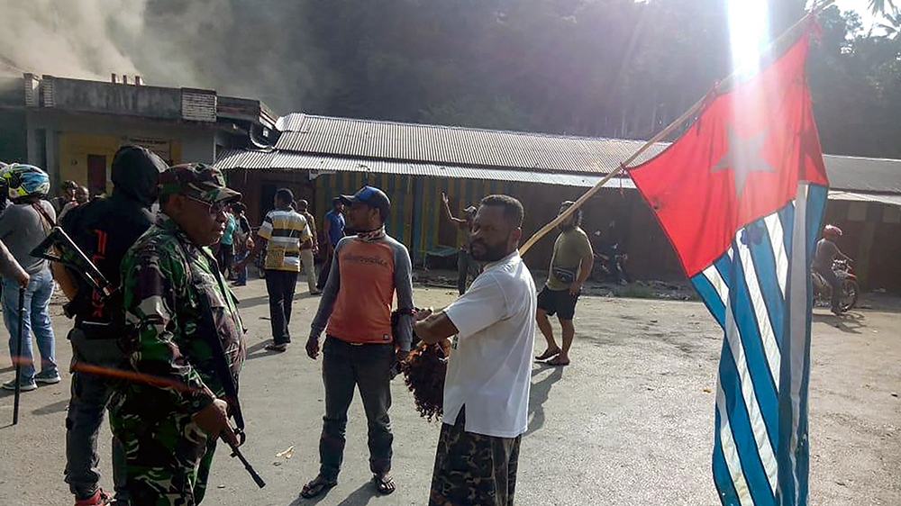 A protester carries the banned Papuan flag as he meets an Indonesian soldier in the city of Fakfak on August 21, 2019. - Indonesia''s Papua was hit by fresh unrest on August 21 as more than 1,000 secur