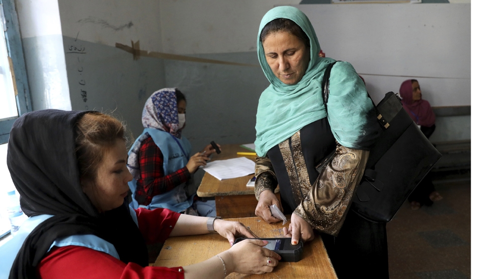 An election official scans a voter’s finger with a biometric device at a polling station in Kabul