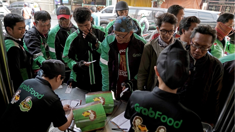 Employees prepare orders for motorcycle drivers at Nanik’s stall in Jakarta.