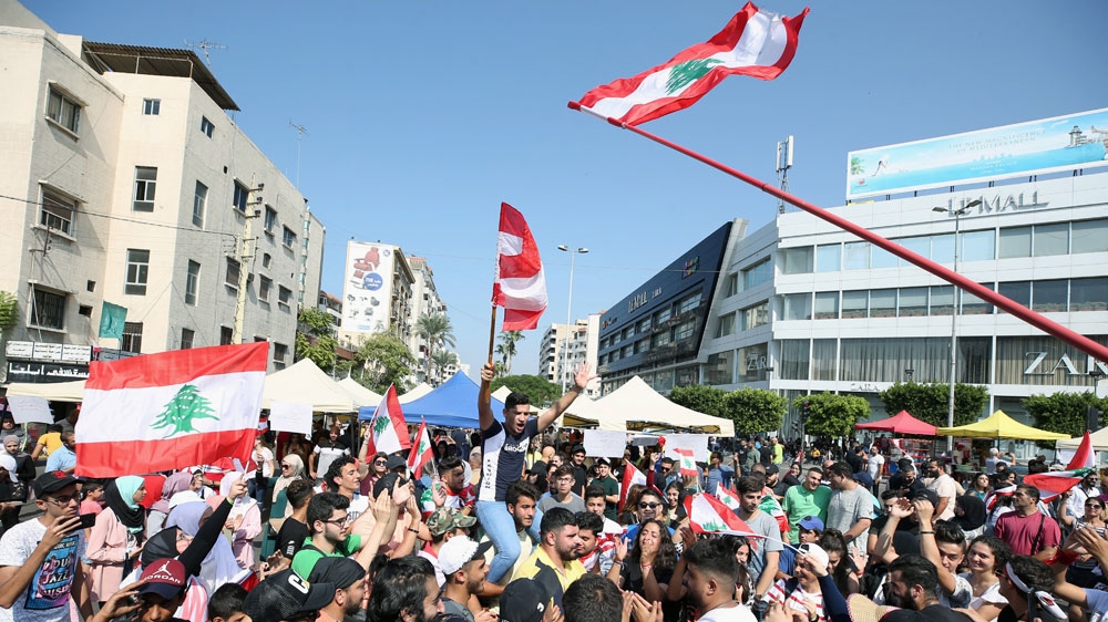 Demonstrators carry national flags and gesture during an anti-government protest in the port city of Sidon