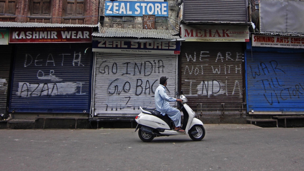 A man rides a scooter in front of a closed shop after the Government tightened restrictions in most parts of the Kashmir, India ahead of scheduled speeches by world leaders including Indian and Pakist
