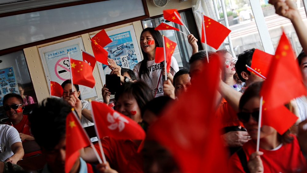 Pro-China supporters sing the Chinese national anthem on a ferry in Hong Kong. The months of protests in the city are an unprecedented challenge to the government in Beijing
