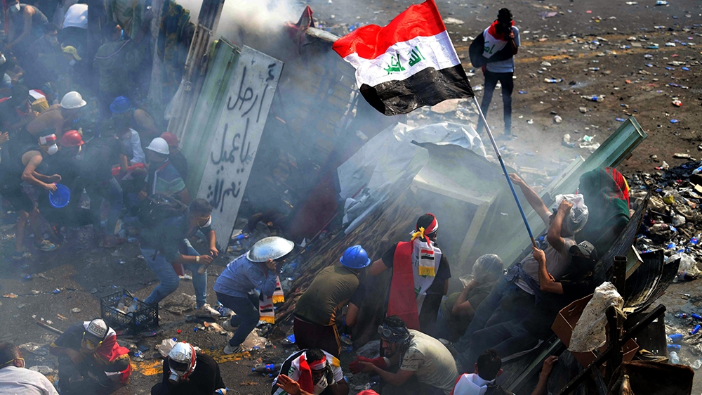  Iraqi protesters take cover during clashes with riot police forces following a demonstration at al-Tahrir square, central Baghdad, Iraq, 29 October 2019. According to media reports, at least 65 peopl