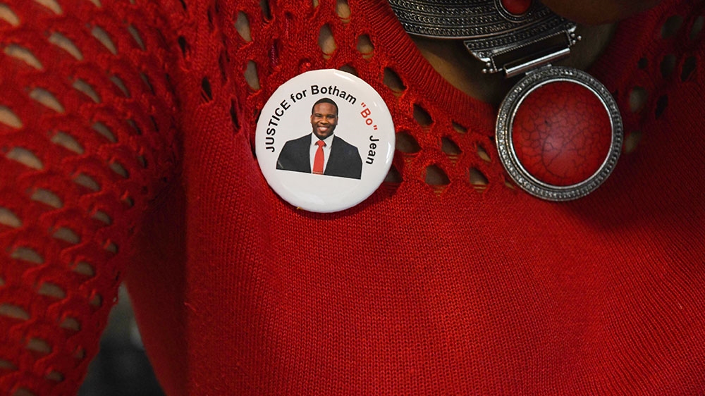 A pin-back button with the image of Botham Jean is seen on Zina West-Lewis as she comes out of the court