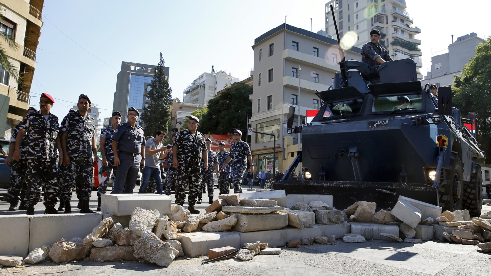 Police remove stones set up by anti-government protesters to block a main road in Beirut, Lebanon, Wednesday, Oct. 30, 2019. There was so significant resistance from protesters as army units with bull