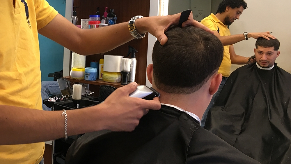 Ashrif gets a haircut at his local barber, like many Tunisians, he says he's lost faith in politicians but trusts Kais Saied  [Sofia Barbarani/Al Jazeera]