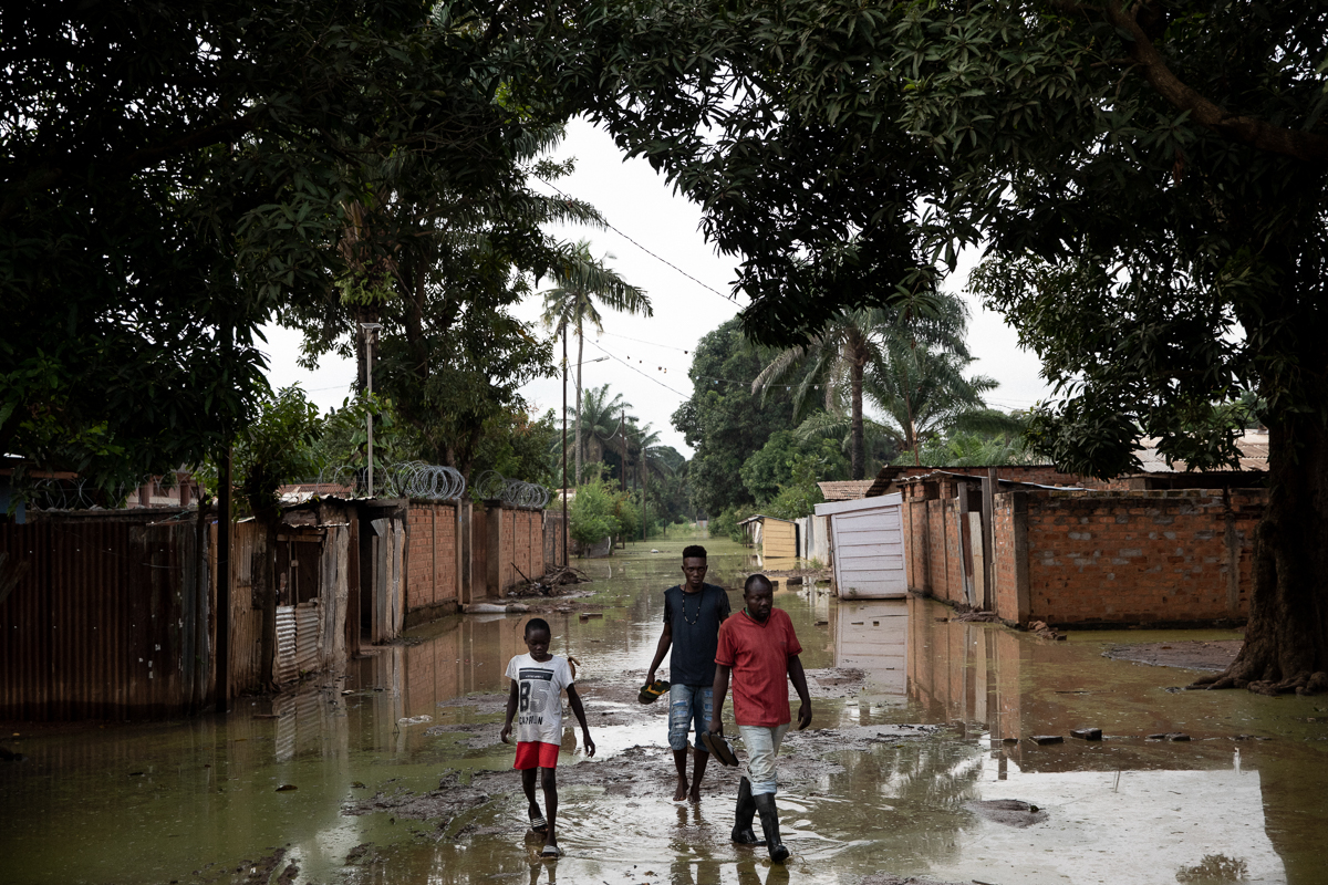 Parfait Madigoto (in red) and two younger neighbours walk in their inundated street, in Bimbo neighbourhood. “Water raised little by little. One morning, we saw it was already inside the house. I got