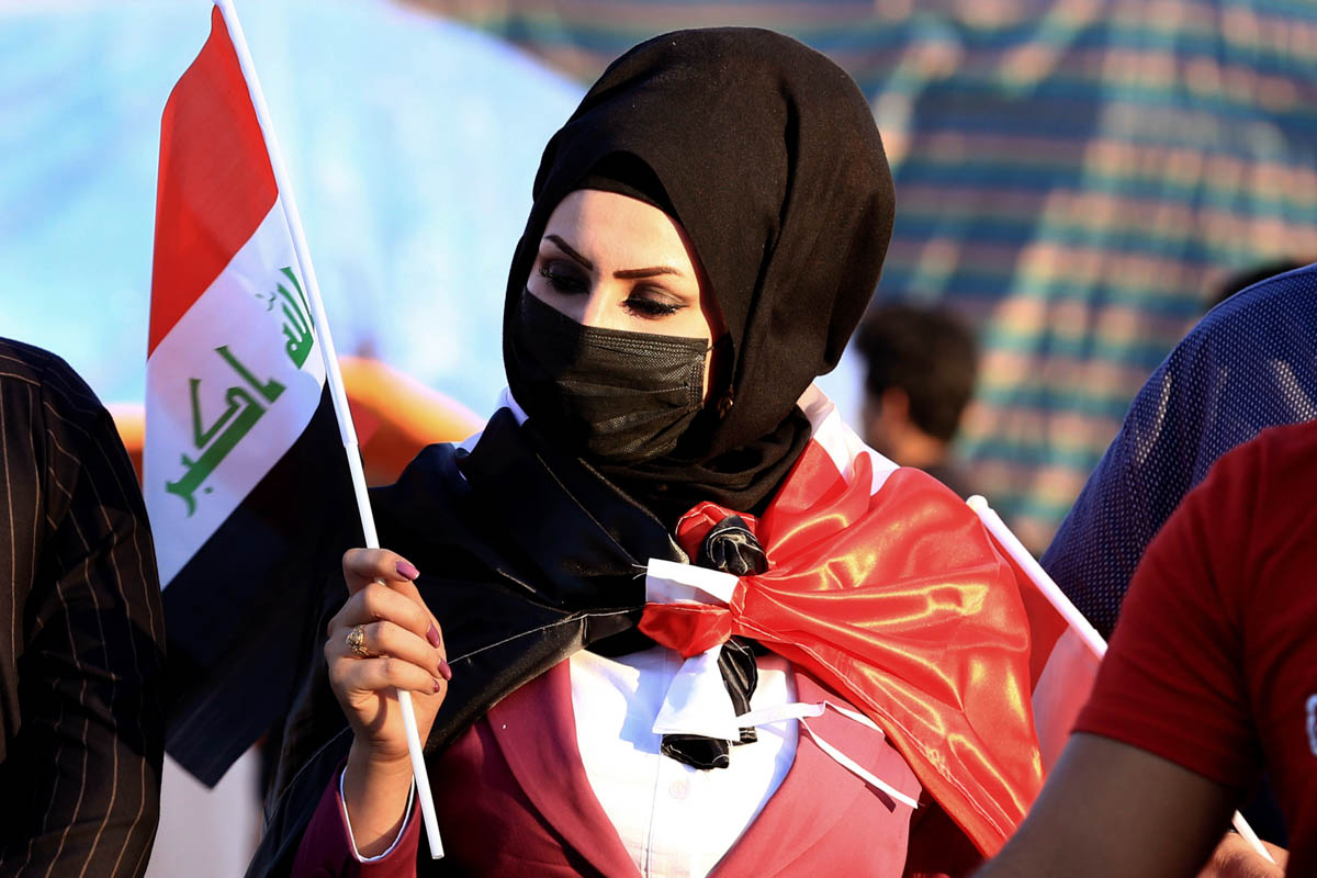 A woman holds a flag as anti-government protesters gather near Basra provincial council building during ongoing protests in Basra, Iraq, Saturday, Nov. 2, 2019. (AP Photo/Nabil al-Jurani)
