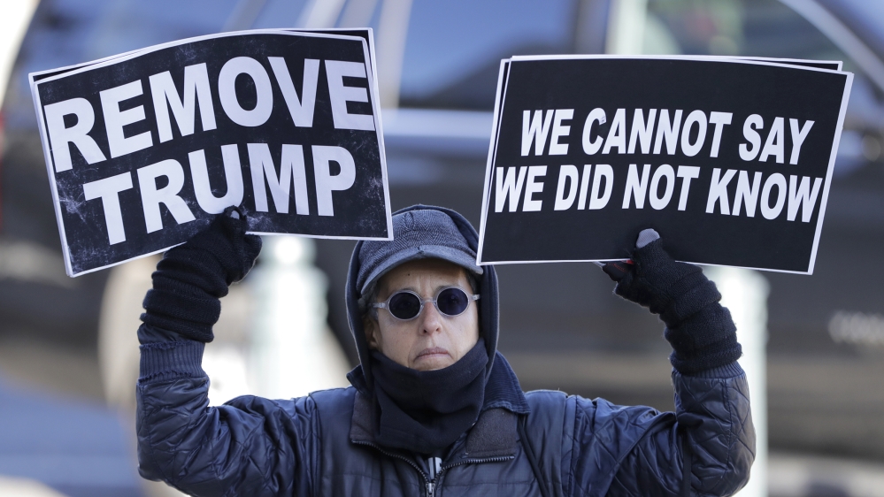 A protestor holds signs outside Longworth House Office Building, where top U.S. diplomat in Ukraine William Taylor, and career Foreign Service officer George Kent, are set to testify before the House