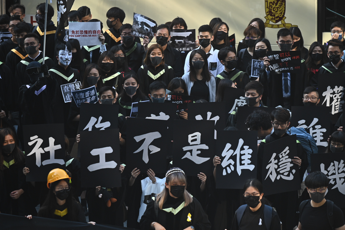 Masked University students display placards and chant slogans during an anti-government protest at their graduation ceremony at the Chinese University of Hong Kong on November 7, 2019. - Hong Kong has