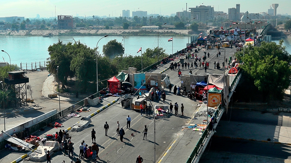 Protesters stage a sit-in between barriers at the Sinak Bridge in Baghdad, Iraq, Thursday, Nov. 21, 2019. Renewed clashes overnight in Baghdad between anti-government demonstrators and security forces