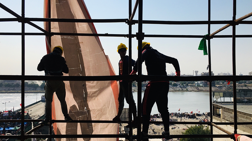  three teenage boys rearrange a banner that reads God is Great [Sofia Barbarani/Al Jazeera]