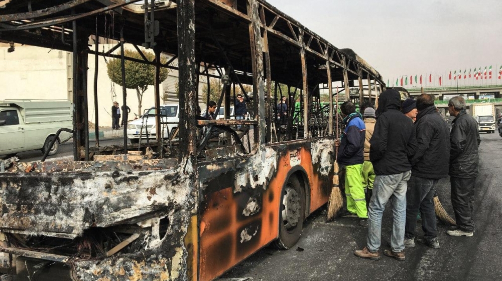 Iranians inspect the wreckage of a bus that was set ablaze by protesters during a demonstration against a rise in gasoline prices in the central city of Isfahan on November 17, 2019. President Hassan