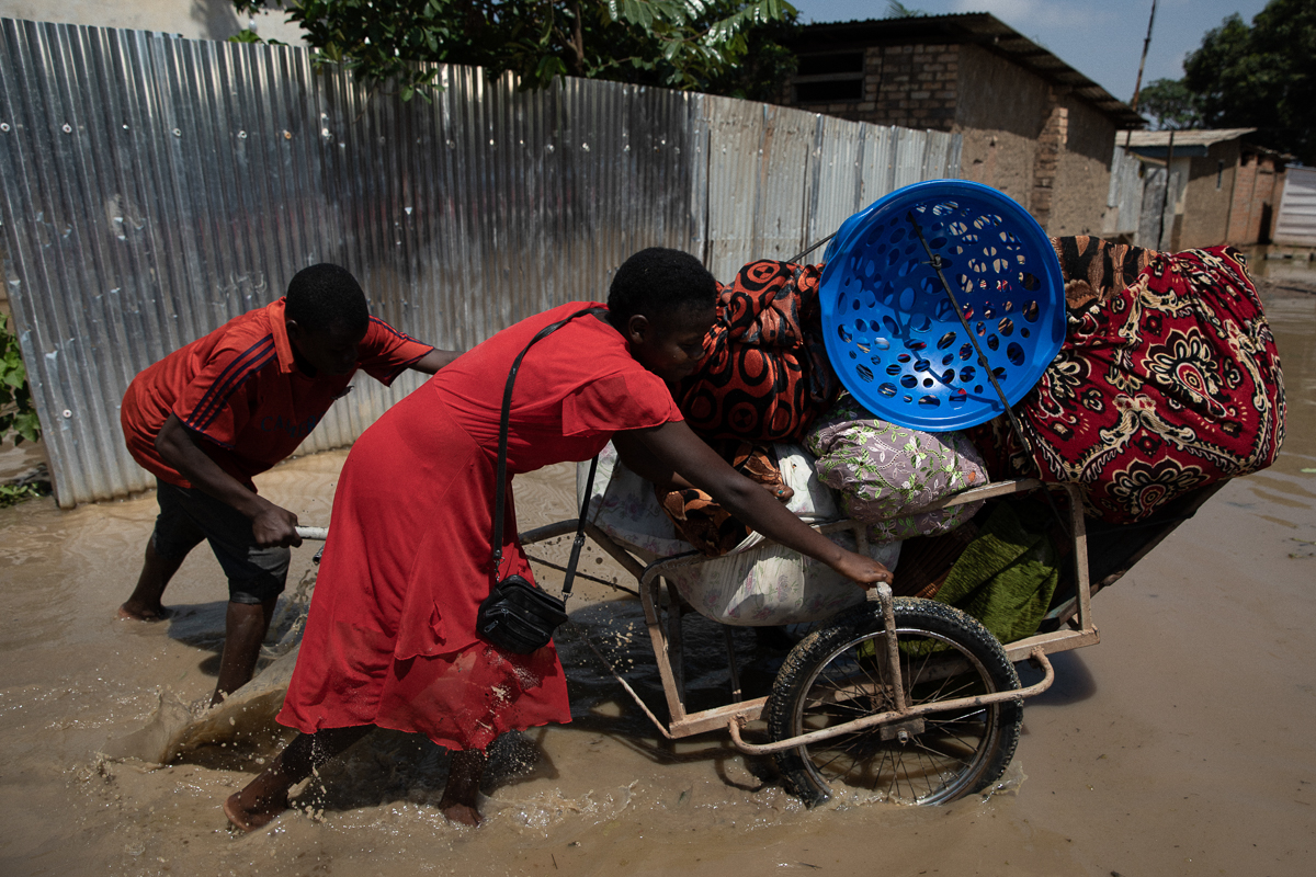Simon and Boubou carry the things of Marguerite Bangui out of her house, as water is raising towards her porch. Marguerite will go live in a house she’s building, farther away from Ubangi River. “I’ve