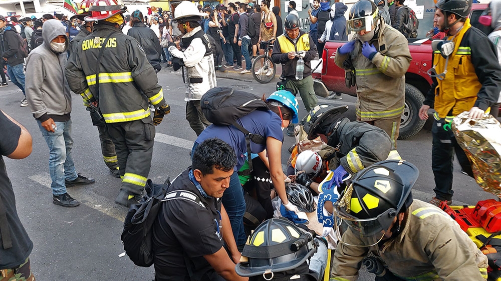 Firefighters assist demonstrators after a car ran over people protesting against the government of Sebastian Pinera in Antofagasta, Chile