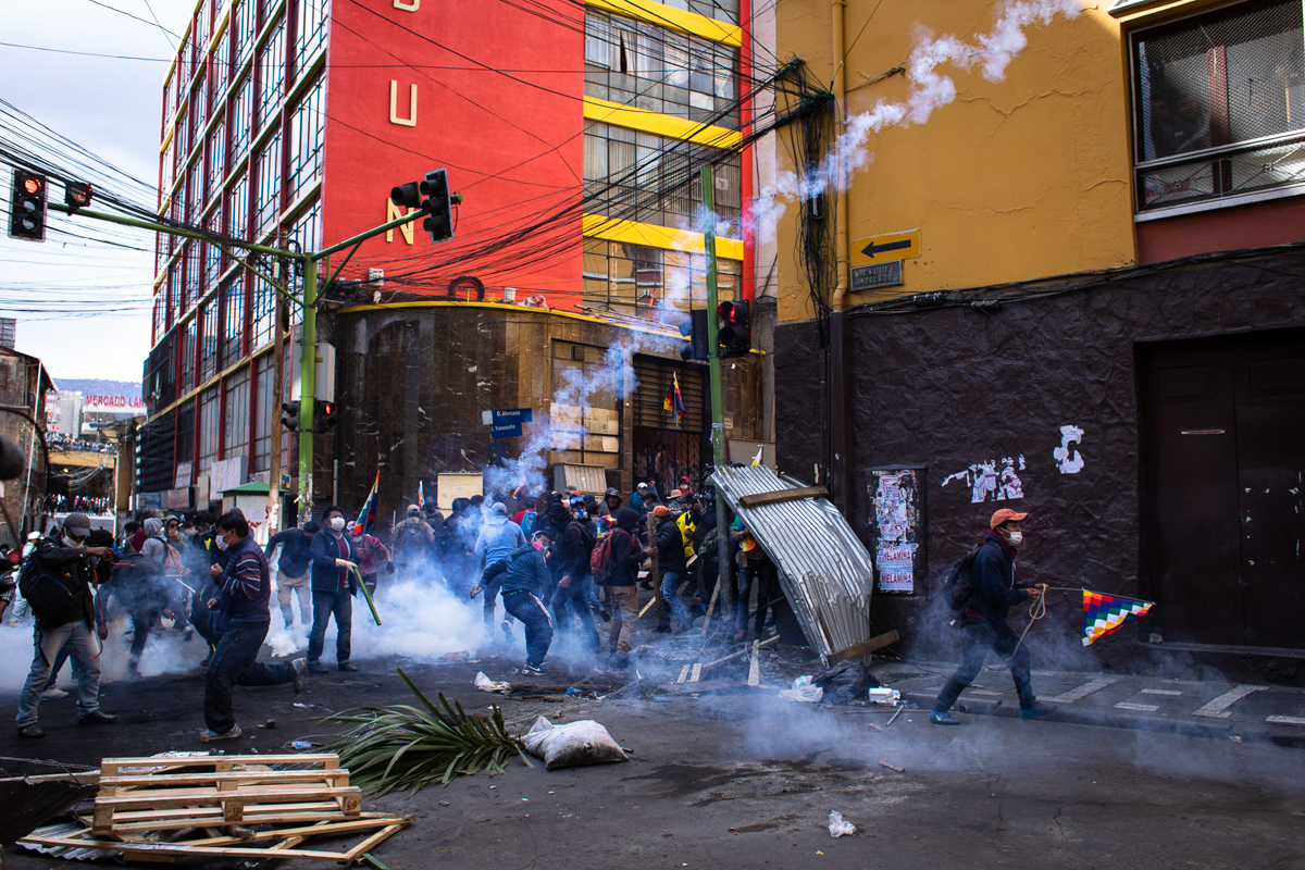Protestors through tear gas canisters back to the police after tearing down a barricade during demonstrations in support of the ousted president Evo Morales La Paz, Bolivia. Nov. 15, 2019 © Erika Pin~