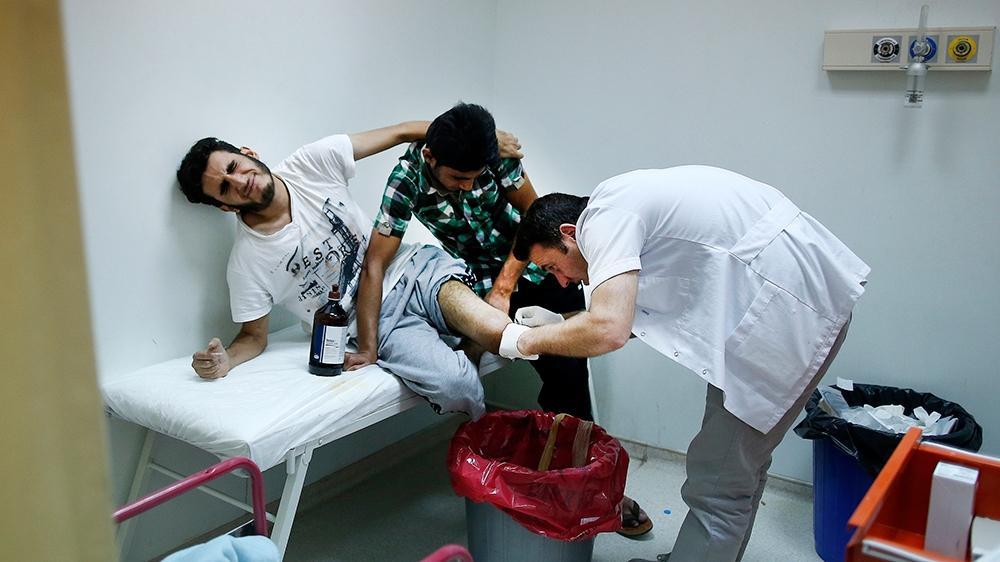 A doctor treats a double amputee Syrian refugee in the hospital at the Oncupinar camp for Syrian refugees next to the border crossing with Syria, near the town of Kilis in southeastern Turkey, Monday,
