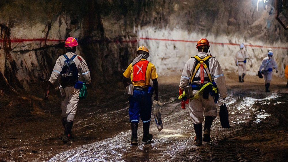 Miners wearing safety equipment walk through an underground tunnel at the South Deep gold mine, operated by Gold Fields Ltd., in Westonaria, South Africa, on Thursday, March 9, 2017