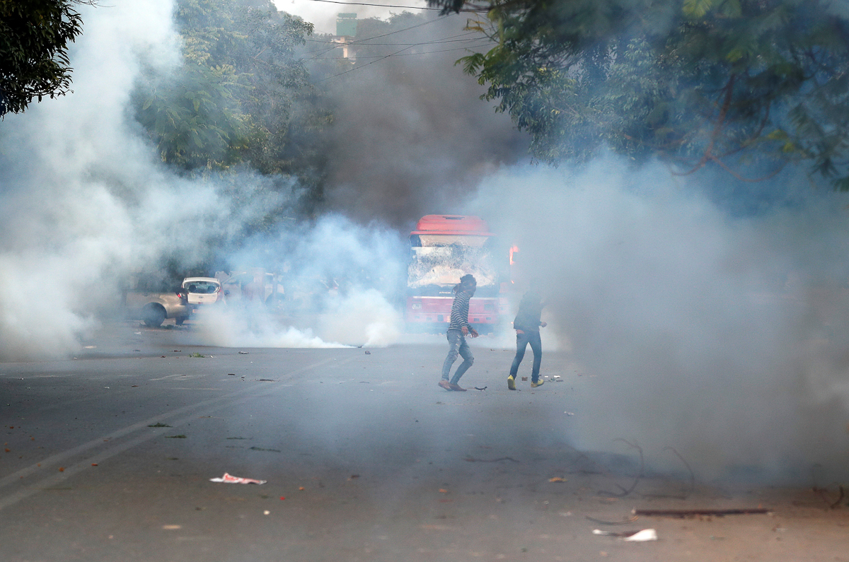 Demonstrators run for cover as smoke billows from a tear gas shell fired during a protest against a new citizenship law in New Delhi, India, December 15, 2019. Picture taken December 15, 2019. REUTERS