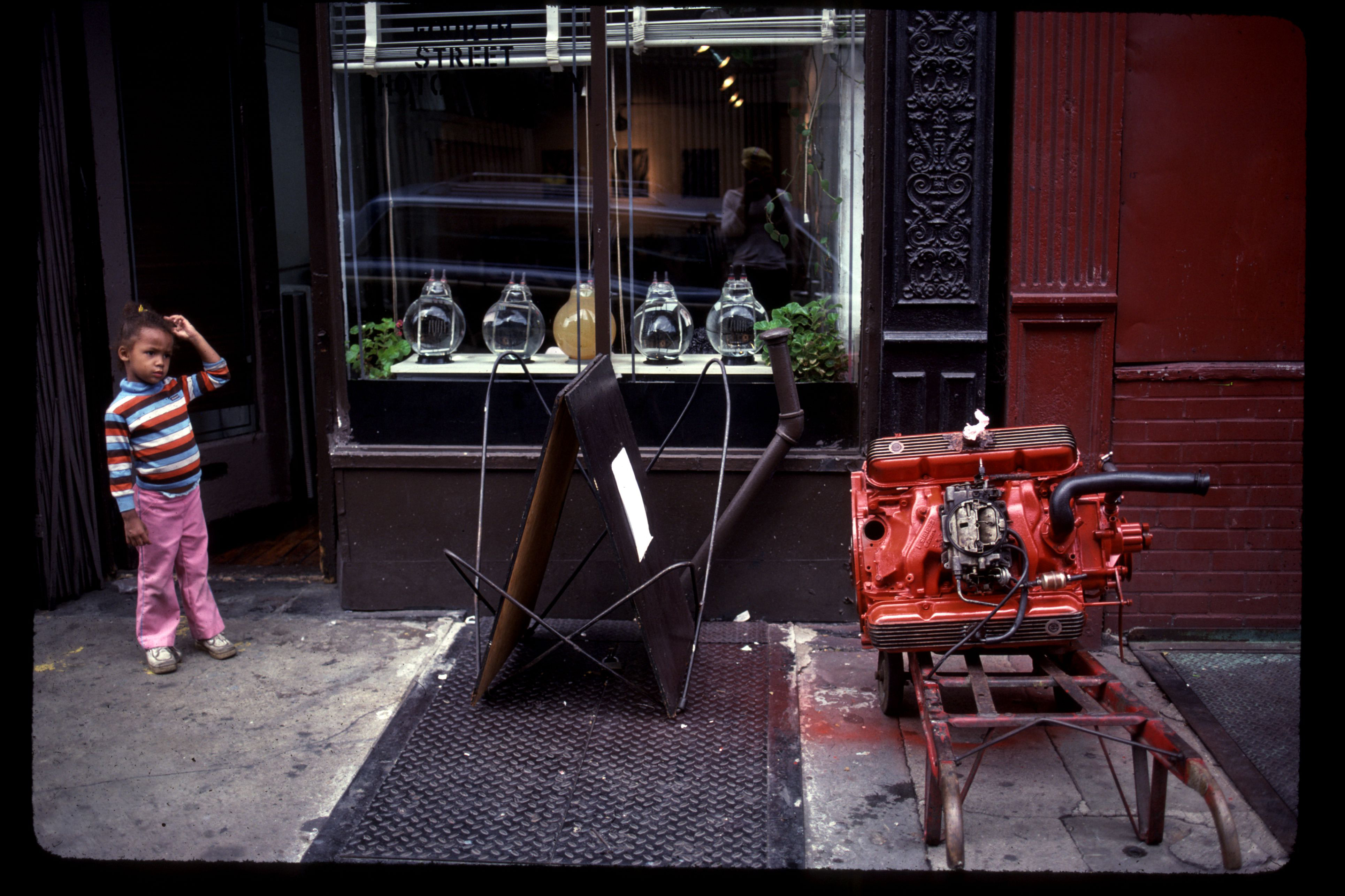 Alex Harsley’s oldest daughter Aleka next to the newly built engine of his 1968 Dodge Dart outside the 4th Street Photo Gallery, 1981 [Photo courtesy: Alex Harsley]