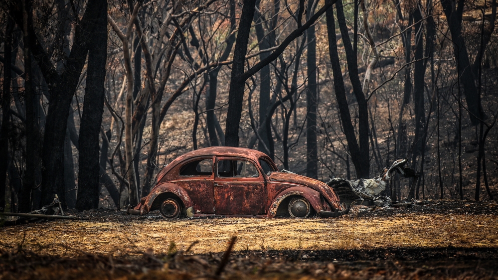 The remains of a car that was destroyed by bushfires sits near a home in the town of Balmoral on December 30, 2019 in Sydney, Australia. Firefighters have made the most of slightly cooler conditions o